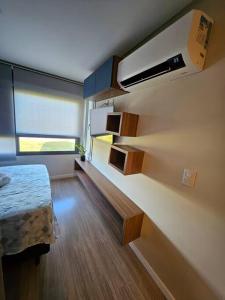 um pequeno quarto com uma cama e uma janela em Loft Flow Parque Una com garagem! em Pelotas