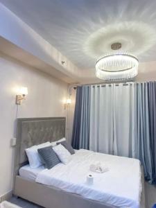 a bedroom with a large white bed with a chandelier at Grace Residences Elevate Escapes in Manila