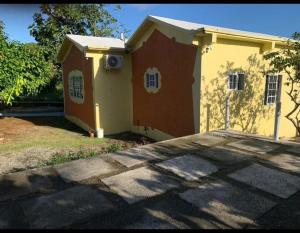 una pequeña casa amarilla y roja con entrada en Yaad Away From Yaad en Manchioneal