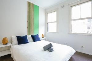 una camera da letto con un grande letto bianco con cuscini blu di Superb 2 Bedroom House Darlinghurst 2 E-Bikes Included a Sydney