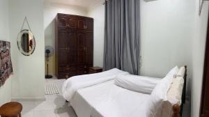 een slaapkamer met een wit bed en een houten kast bij Mutiara Villa Homestay - Comfort Away From Home in Merlimau