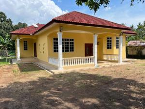 una pequeña casa amarilla con techo rojo en Mutiara Villa Homestay - Comfort Away From Home en Merlimau