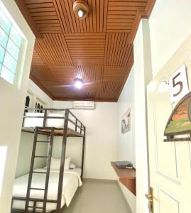 a bedroom with bunk beds and a wooden ceiling at Sentosa Lodge in Kampungdurian