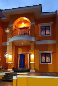 a large yellow house with a balcony on top of it at Manyak Villa at Berastagi Resort C14 Jl Mimpin Tua in Berastagi