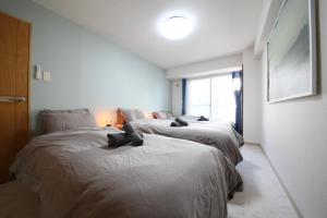 Duas camas num pequeno quarto com uma janela em AMS TOWER 806 em Sapporo