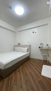 a white bedroom with a bed and a desk at FUNDI Hotel in Tainan