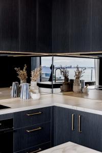 a kitchen with black cabinets and a window with plants at Balmoral on Scott - Harbour Front Perfection in Newcastle