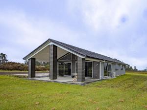 Volcanic Views - Horopito Holiday Home في أوهاكيون: منزل بسقف أسود على حقل أخضر