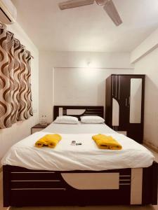 a bedroom with a large bed with yellow towels on it at Namaste Nirvana Appartments in Daman