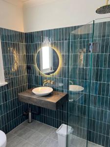 un bagno piastrellato verde con lavandino e specchio di Native Rose Hotel a Sydney