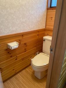 a bathroom with a toilet with wooden walls and a window at King's house in Hakuba