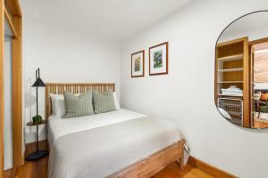 a white bedroom with a bed and a mirror at Balmain Retreat - 2BR + Study in Sydney