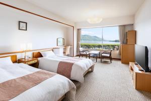 una camera d'albergo con due letti e una TV a schermo piatto di Amano Hashidate Hotel a Miyazu
