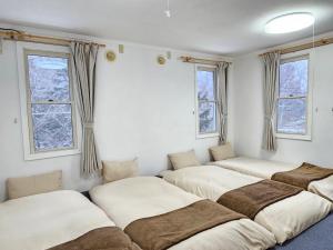 a row of beds in a room with windows at guest house White House ホワイト ハウス in Shimukappu