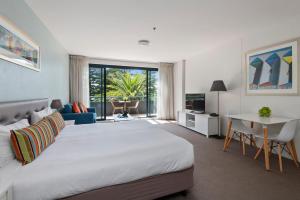 a bedroom with a large white bed and a table at Quest Cronulla Beach in Cronulla