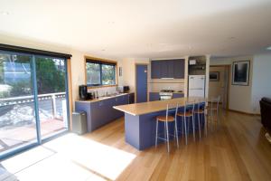 a kitchen with a counter and chairs in a room at Waterline Holiday Home in Coles Bay