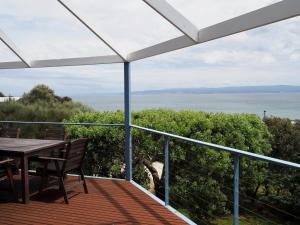 a balcony with a table and chairs and the ocean at Waterline Holiday Home in Coles Bay