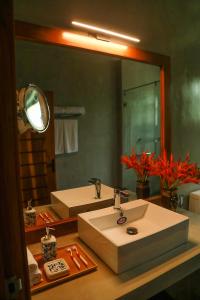 La salle de bains est pourvue d'un lavabo et d'un grand miroir. dans l'établissement Villa Rumassala Luxury Chalets Unawatuna, à Unawatuna