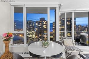 a living room with a table and a large window at Beautiful Bright Modern Condo with Water view and AC in DT Vancouver 2BR,3BD,2BT sleeps 6 guests Free parking Netflix Included in Vancouver