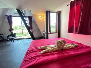 a bedroom with a red bed with two wooden hearts on it at บ้านริมน้ำ สำหรับครอบครัว in Buriram