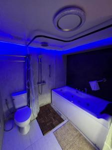 baño con aseo y bañera con luz azul en CLOCKWORKORANGE Luxury Suites en Isla de Mactán