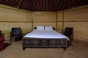a bedroom with a bed in a room with two chairs at SAFARI-Glamping in Al Wāşil