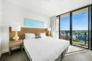 a bedroom with a large bed and a large window at Oaks Redcliffe Mon Komo Suites in Redcliffe