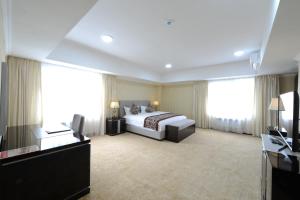 a large hotel room with a bed and windows at Alpha Hotel Ulaanbaatar in Ulaanbaatar