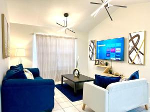 sala de estar con 2 sofás azules y TV en Traveler Stay PLUS, en Eagle Pass