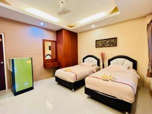 een slaapkamer met 2 bedden en een spiegel bij Benwadee Resort Pattaya in Ban Pong