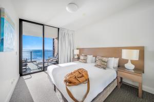 a hotel room with a bed with a bag on it at Oaks Redcliffe Mon Komo Suites in Redcliffe