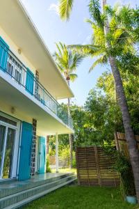 a house with blue doors and a palm tree at villa Anthalo in La Saline les Bains