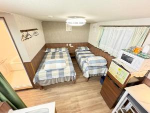 Habitación pequeña con 2 camas y TV. en SHINJUKU WARM VILLA I, en Tokio