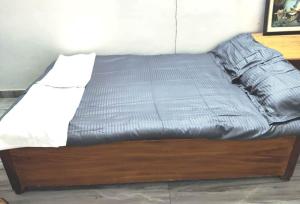 a bed with a wooden frame with a gray comforter at Sweet Home,Stay with Maneesha&Ajay 3Rooms Kitchen in Lucknow