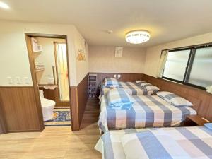 two beds in a room with a bathroom at SHINJUKU WARM VILLA I in Tokyo