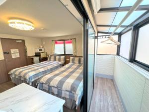 two beds in a room with windows at SHINJUKU WARM VILLA I in Tokyo