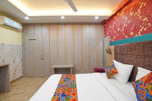 Kakarmatha的住宿－FabHotel RS Residency，一间卧室配有一张床,墙上挂着绘画作品