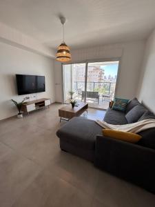 a living room with a couch and a tv at Sea Breeze Netanya Retreat by Sea N' Rent in Netanya