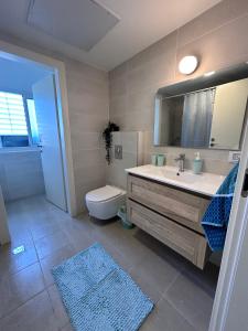 La salle de bains est pourvue d'un lavabo, de toilettes et d'un miroir. dans l'établissement Sea Breeze Netanya Retreat by Sea N' Rent, à Netanya