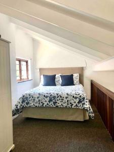 1 dormitorio con 1 cama con almohadas azules en Sherwood Garden Cottage en Durban