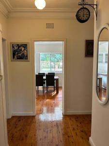 a dining room with a table and a clock on the wall at 3 BDR house close to train station, airport & City in Sydney