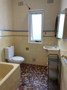 a bathroom with a toilet and a sink and a tub at 3 BDR house close to train station, airport & City in Sydney