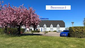 une voiture bleue garée devant un immeuble avec un arbre à fleurs dans l'établissement Le Pavillon de Rouen, à Franqueville-Saint-Pierre