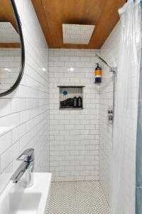 y baño de azulejos blancos con ducha y lavamanos. en Blue Moon Tiny House, Sauna,ht, en Port Angeles