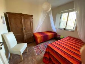 ein Schlafzimmer mit einem Bett, einem Stuhl und einem Fenster in der Unterkunft Seele baumeln lassen im Olivenhain (Meeresnähe) in Santa Caterina dello Ionio