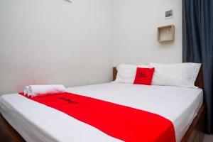 a bedroom with a red blanket on a bed at RedDoorz Syariah near Pascasarjana UGM 3 in Yogyakarta