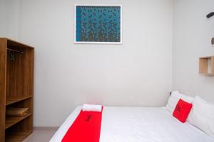 a bedroom with a white bed with red pillows at RedDoorz Syariah near Pascasarjana UGM 3 in Yogyakarta