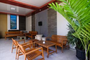 a patio with wooden chairs and tables and a plant at RedDoorz Syariah near Pascasarjana UGM 3 in Yogyakarta