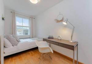 1 dormitorio con cama, escritorio y ventana en Kensington & Chelsea - Stylish Apartment in Central London, en Londres