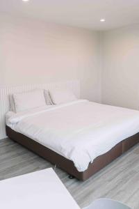 a white bedroom with a large bed with white sheets at Ma Non Nont Hotel & Apartment in Nonthaburi